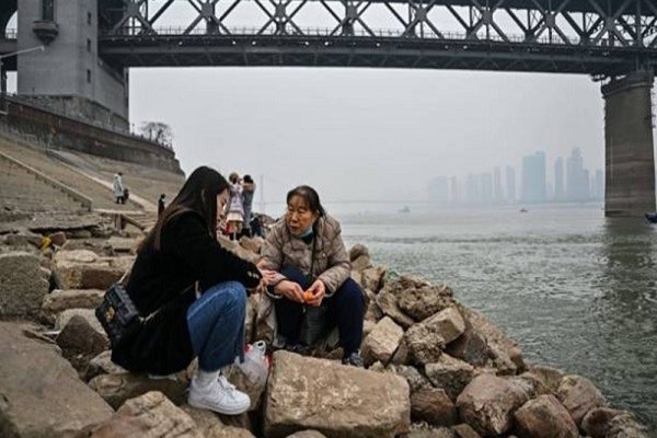 一位老妇人和一名女孩在武汉的长江江畔交谈。（HECTOR RETAMAL/AFP via Getty Images）