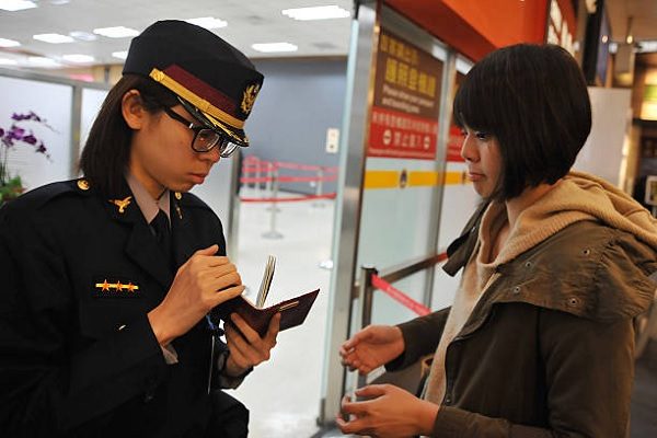 民众从松山机场出国时，接受安检人员查看护照。数据图片。（Mandy Cheng/AFP via Getty Images）