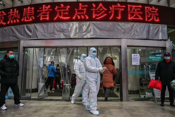 医务人员身穿防护服，帮助阻止一种始于该市的致命病毒的传播，他们于 2020 年 1 月 25 日走在中国中部湖北省武汉市的武汉红十字医院外。 (Photo by HECTOR RETAMAL/AFP via Getty Images)
