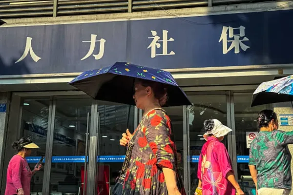 几位老年妇女撑着伞走过重庆市人力资源和社会保障局的办公室门口。(Photo by Cheng Xin/Getty Images)