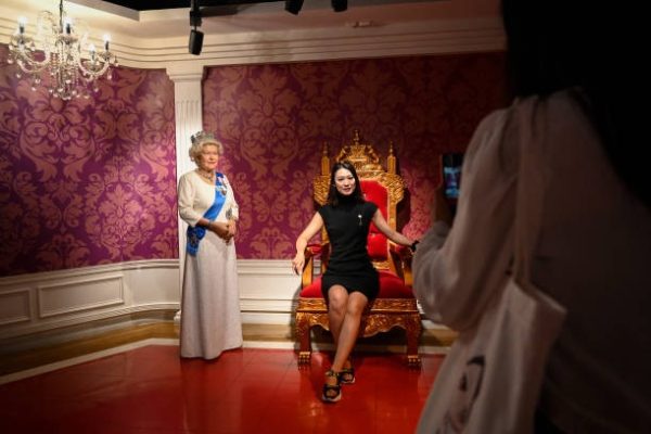 一名女士於2022年9月9日在北京杜莎夫人蠟像館與英國女王伊莉莎白二世蠟像合影。（JADE GAO/AFP via Getty Images）