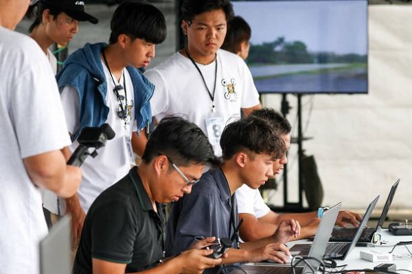 台湾的虎尾科技大学学生2024年10月16日在嘉义举行的第二届国防应用无人机挑战赛上合作操作一架多旋翼无人机。（I-HWA CHENG/AFP via Getty Images）