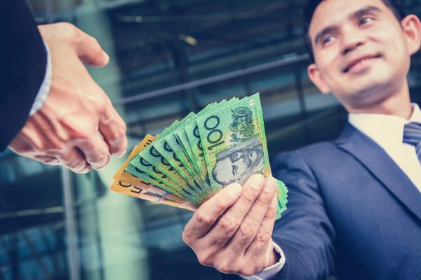 Businessmen passing money, Australia dollar bills