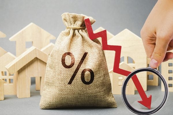 Money bag with percents, down arrow and miniature houses. The concept of low interest rates on mortgage loans or rentals. The percentage of real estate sales. Tax interest. Loan secured. Drop and fall