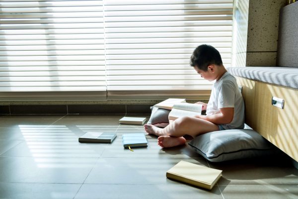 Little boy sitting on floor and reading a book